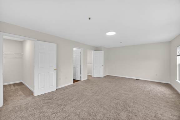 A spacious room with carpeted floor and white walls.