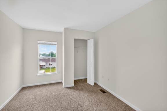 A room with a carpeted floor, a window, and a door.