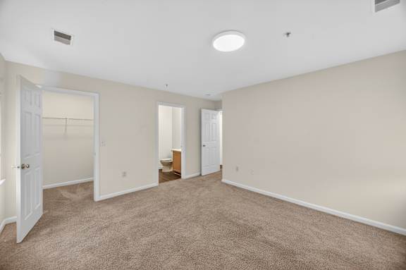 A large, empty room with carpeted flooring and white walls.