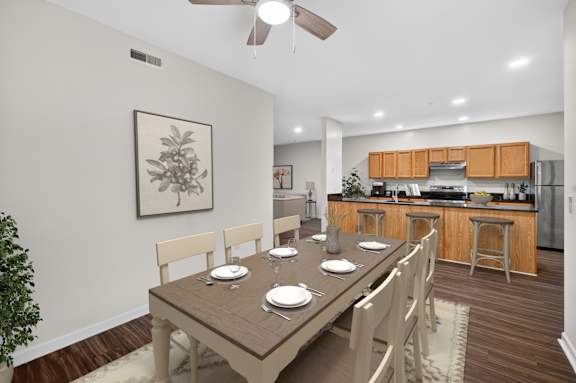 A dining room with a table set for six with a view of the kitchen.