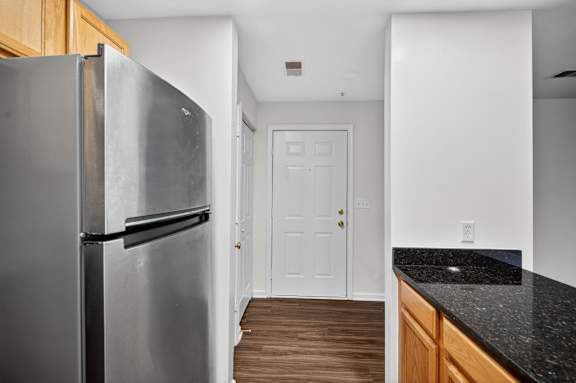 A black fridge in a kitchen with a white door.