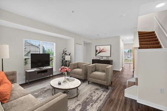 A living room with a grey sofa, a white coffee table, and a brown armchair.