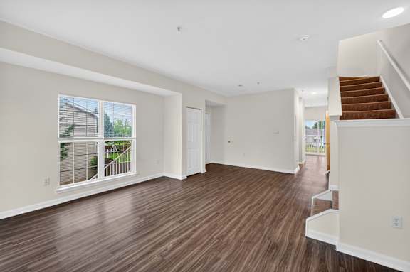 A spacious living room with hardwood floors and a staircase leading to another level.