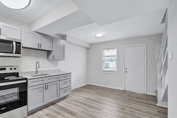A kitchen with a stove, microwave, and cabinets.