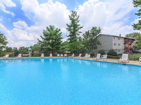 a large blue pool with chairs and a building