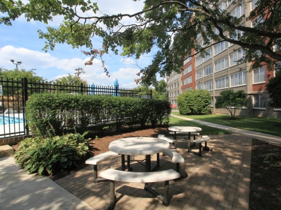 a patio with tables and benches next to a swimming pool
