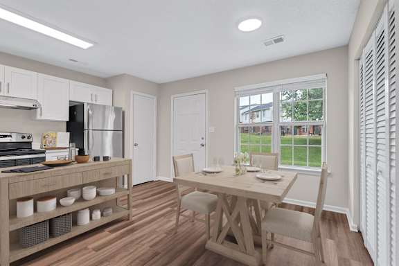 A kitchen with a table and chairs in front of a window.