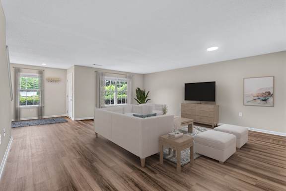 A living room with a white couch and a television on the wall.