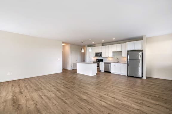 an empty living room and kitchen with a wood floor