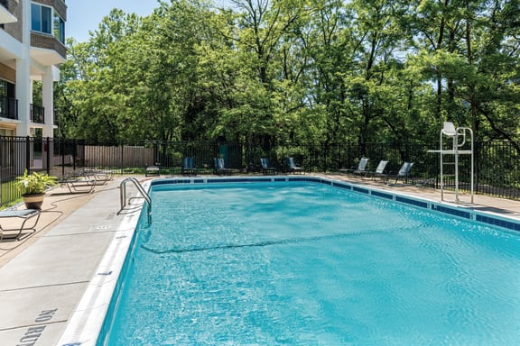 a swimming pool with chairs and trees in the background