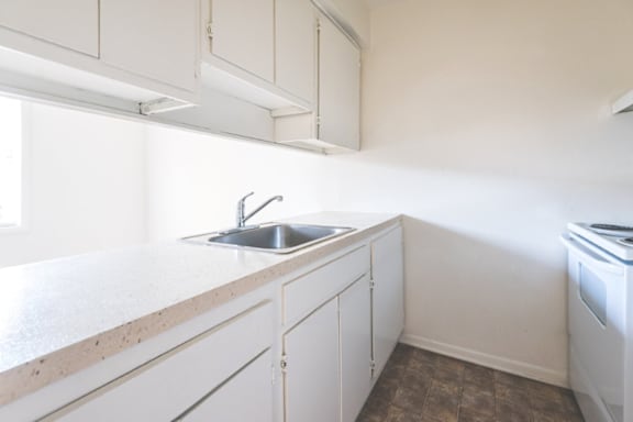 A kitchen with white cabinets and a sink.