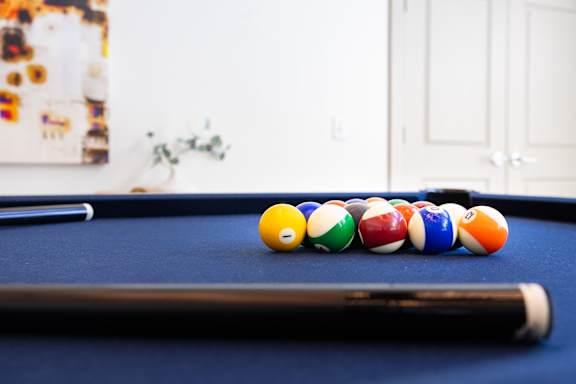 A pool table with a cue stick and balls.