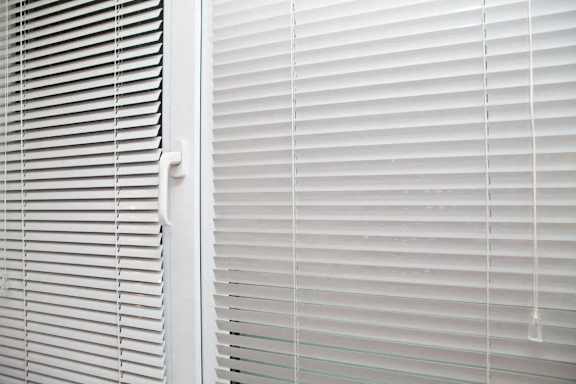 A close up of white horizontal blinds on a window.
