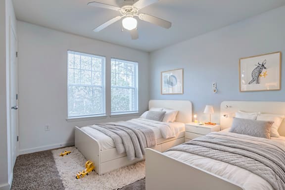 A bedroom with two beds and a ceiling fan.