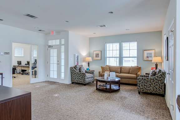 A living room with a brown carpet and furniture.