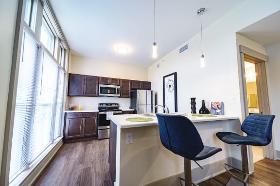 a kitchen and living room with a bar and chairs and a window at Art Lofts at Dayton Arcade apartments in Dayton, OH