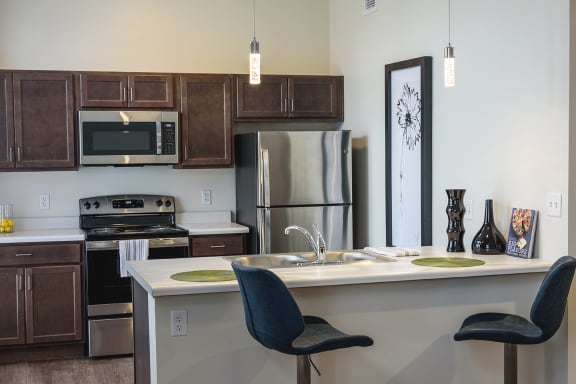 a kitchen with stainless steel appliances and a counter with two chairs at Art Lofts at Dayton Arcade apartments in Dayton, OH