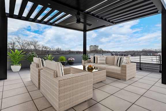 A patio with a wicker sofa and a table with a plant on it.