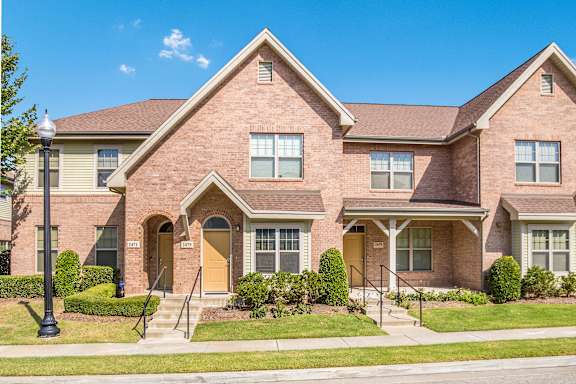 A brick house with a brown door and windows.