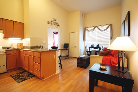 Kitchen and Living Room in a senior living apartment at Cambridge Heights: light Oak cabinets and hardwood flooring