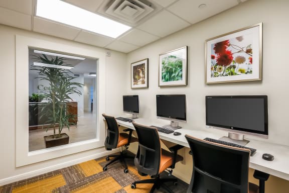 three computer desks in a room with three monitors
