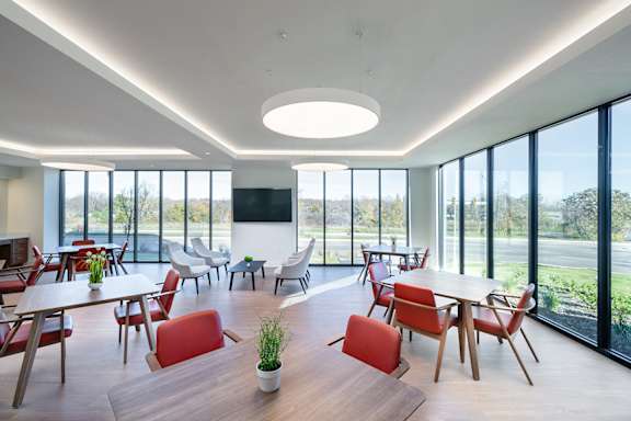 A modern dining room with red chairs and a wooden table.