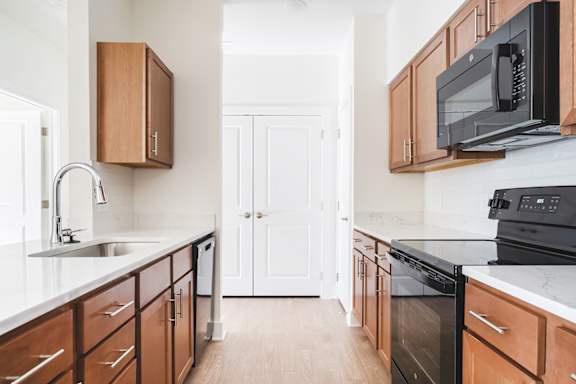 A kitchen with black appliances and wooden cabinets.