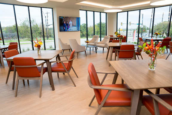 A room with tables and chairs and a TV on the wall.