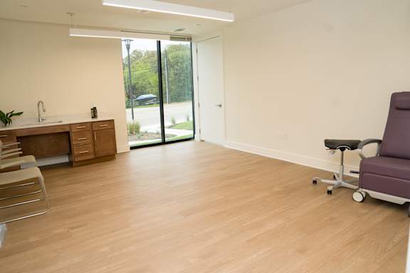 A room with a purple chair and wooden floors.
