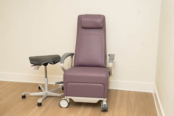 A purple chair with wheels and a footrest is in a room.