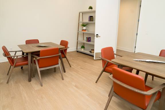 A room with a table and chairs and a bookshelf.