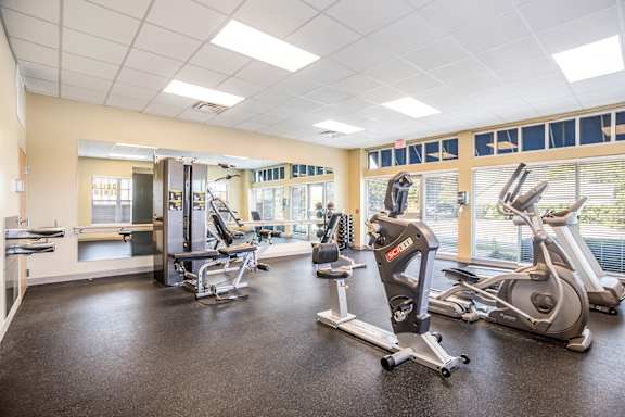A gym with a treadmill, elliptical machines, and other exercise equipment.
