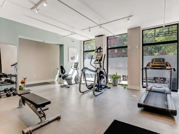 the gym has plenty of exercise equipment and floor to ceiling windows