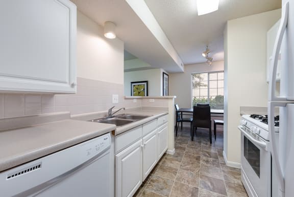 an open kitchen with white appliances and a dining room with a window at Heritage Park Apartments and Townhomes in Minneapolis, MN