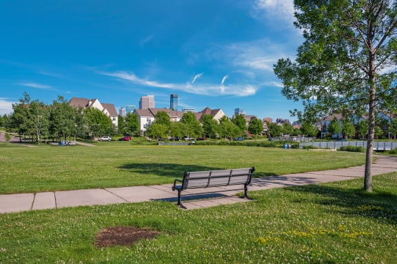 a park bench in a park with a city in the background at Heritage Park apartments and townhomes in Minneapolis, MN