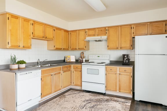 a kitchen with white appliances and wooden cabinets at Horace Mann Apartments and Townhomes in Gary, IN