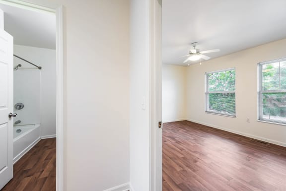 an empty bedroom and bathroom with wood flooring and a ceiling fan at Horace Mann apartments and townhomes in Gary, IN
