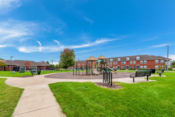 a park with a playground, bike racks, and benches in front of a building at Horace Mann apartments and townhomes in Gary, IN