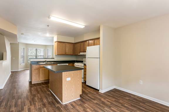 A kitchen with a white refrigerator and wooden cabinets.