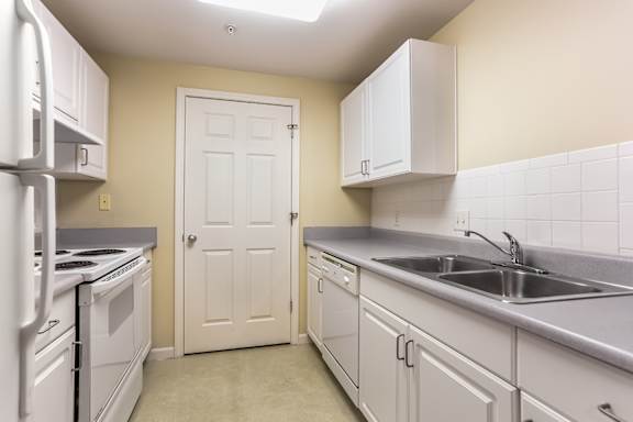 A kitchen with white appliances and cabinets.