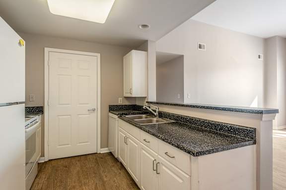 A kitchen with white cabinets and a black countertop.