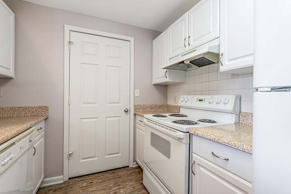 A white door is in a kitchen with white cabinets.