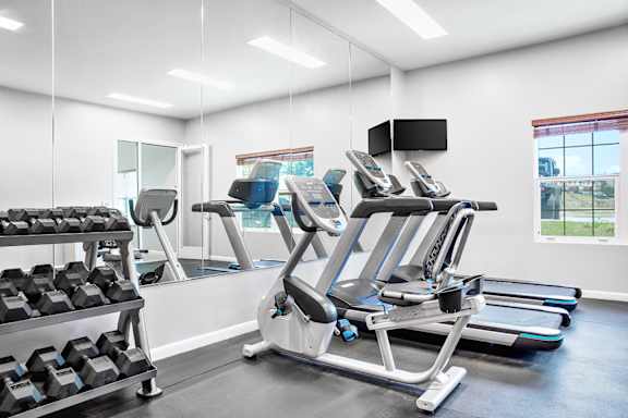 A gym with treadmills, exercise bikes, and dumbbells.