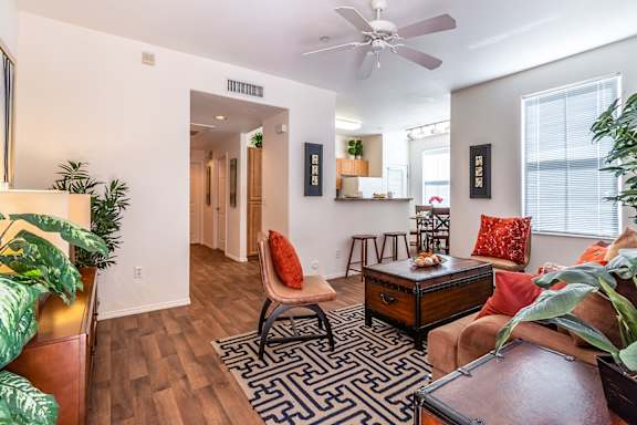 A living room with a black and white rug, a brown couch, and a ceiling fan.
