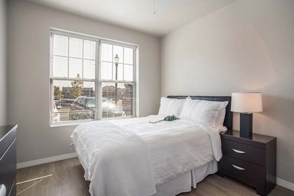 A bedroom with a large bed and a window overlooking a street.