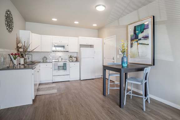 A kitchen with white cabinets and a wooden floor.