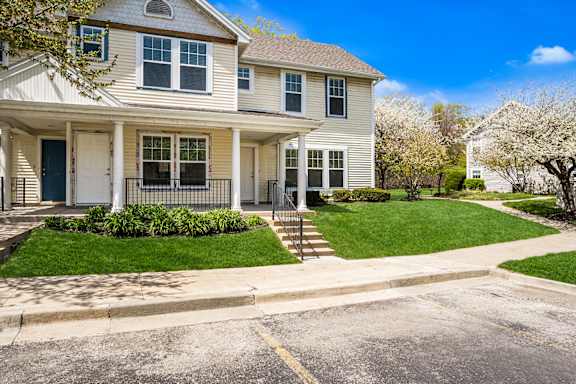 A two-story house with a front porch and a green lawn.
