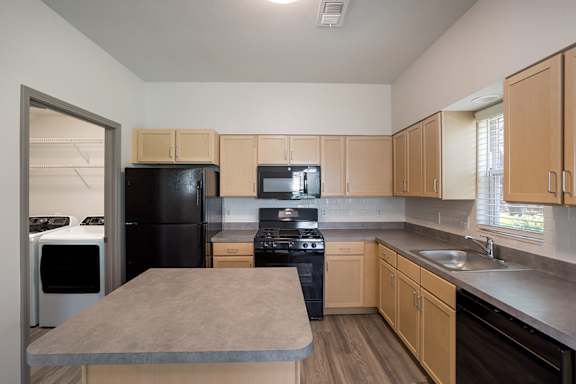 A kitchen with black appliances and wooden cabinets.