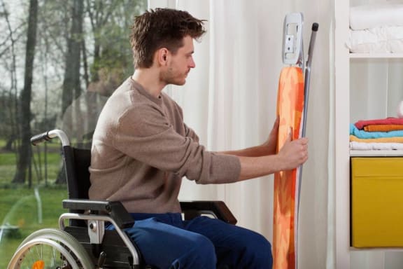 Man on wheelchair doing chores-Longfellow Heights Apartments, Kansas City, MO