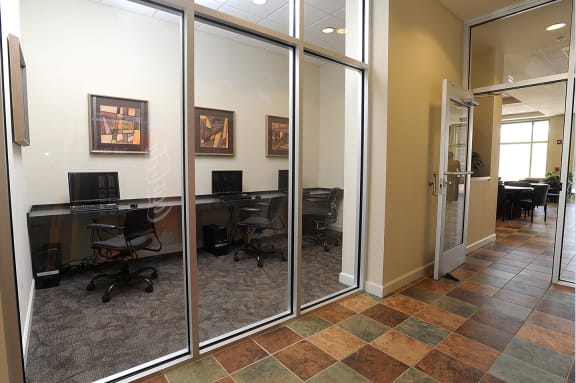 a conference room with glass doors and a desk with a computer